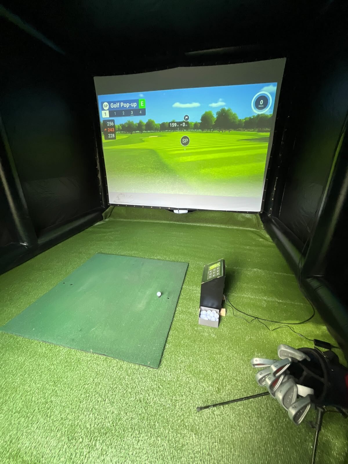 Interieur van de GolfPopup golfsimulator met projectiescherm en launch monitor